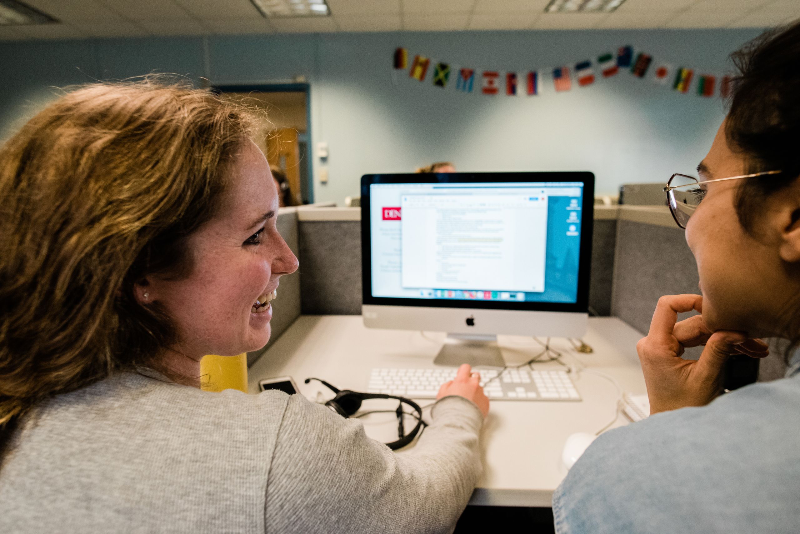 Student is talking with a journalist in front of a computer screen.
