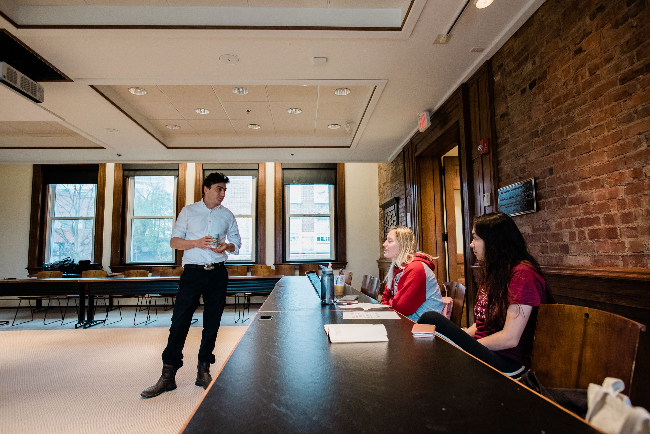 Jesse Dukes speaks with two students who are sitting at a table.