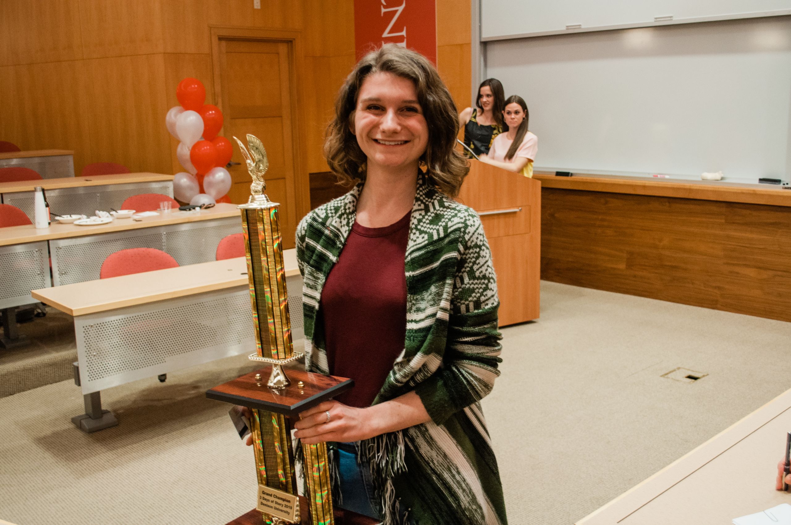 A woman stands with a large trophy