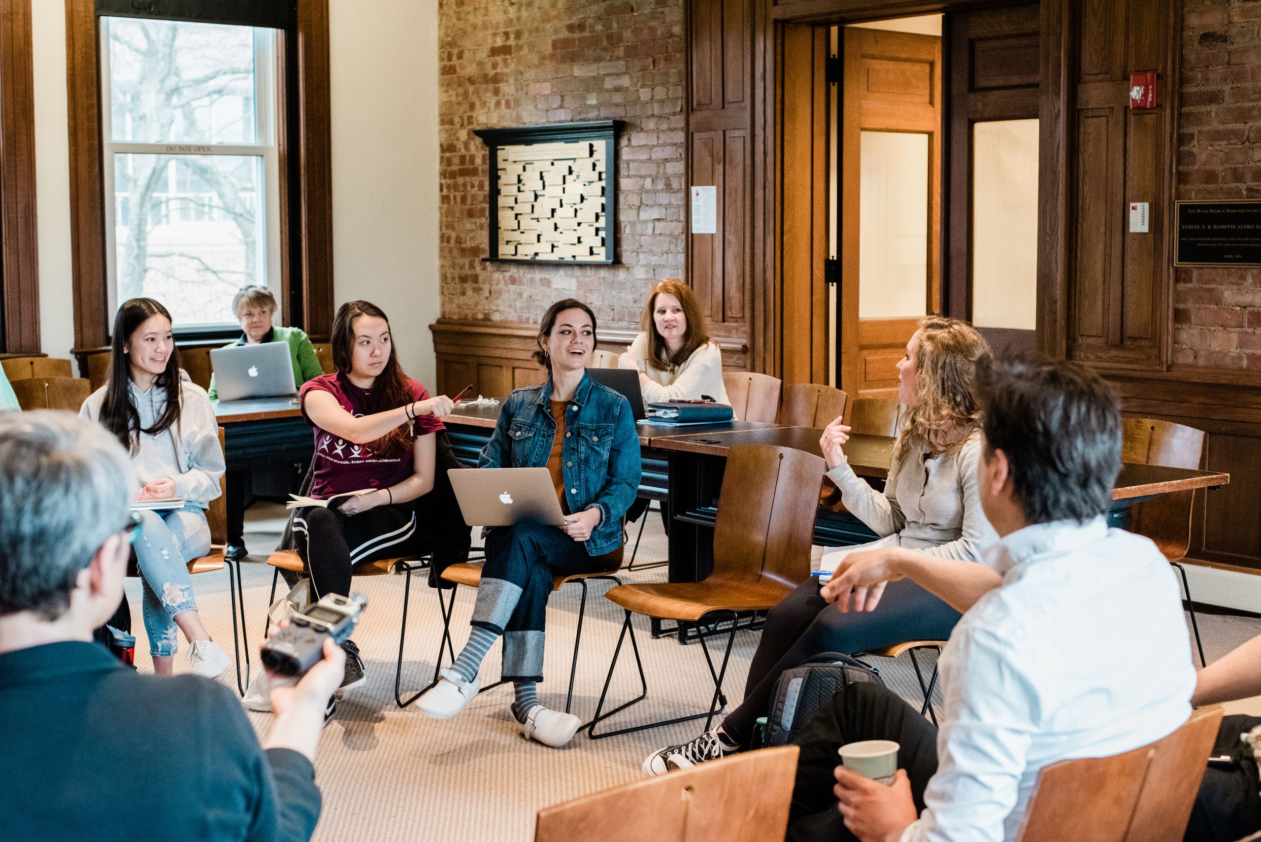 Students sit in a circle focused on one of them talking.